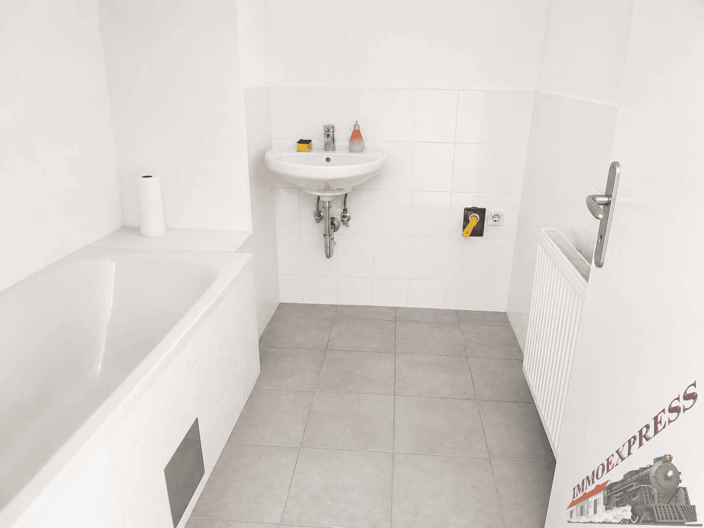 Funktionales Badezimmer mit Badewanne, Waschbecken und weißen Wandfliesen, in gutem Zustand.