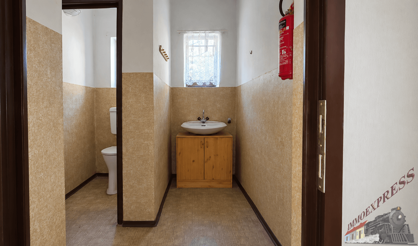 Gäste-WC mit Toilette, Waschbecken auf Holzunterschrank und gemusterter Tapete, mit Fenster.