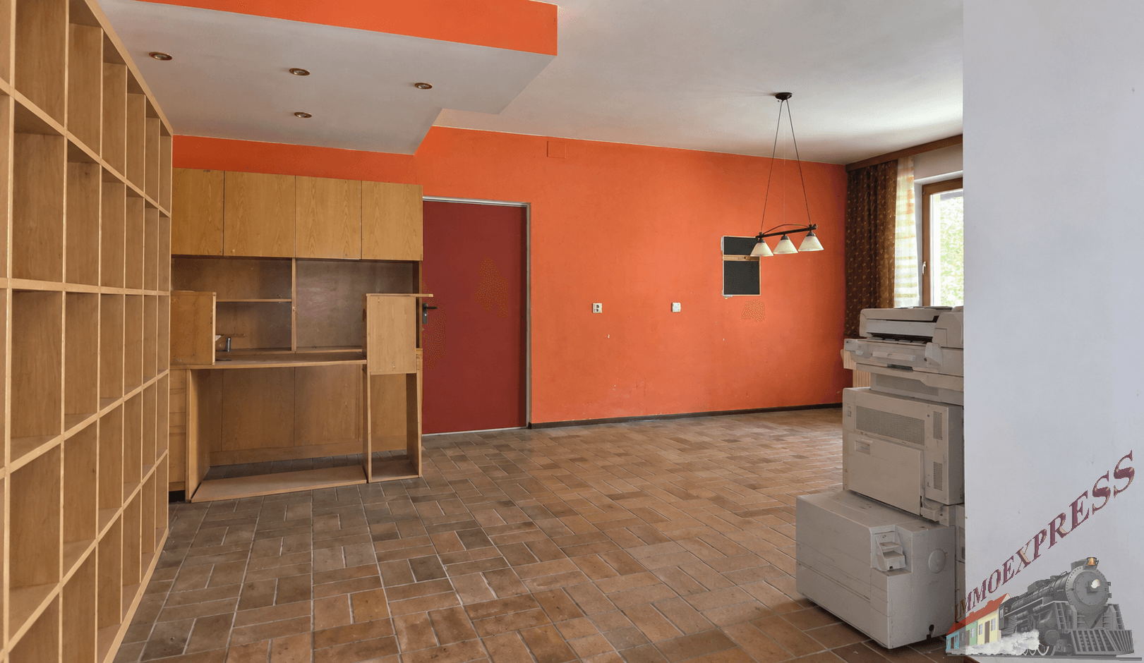 Großer Raum mit orangefarbenen Wänden, Fliesenboden und eingebauten Holzregalen, ideal als Büro.