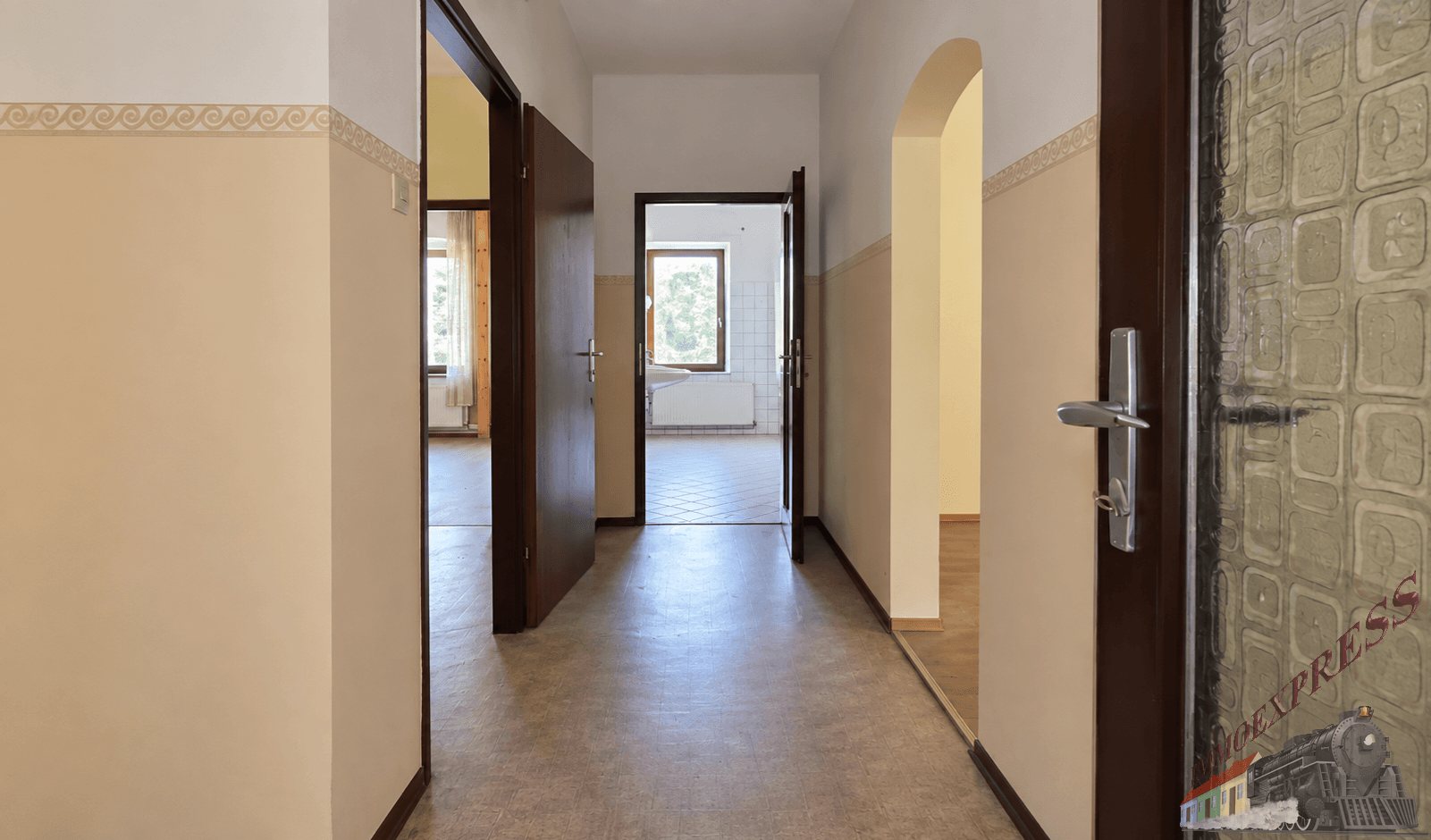 Heller Flur mit Laminatboden und mehreren Türen, die zu anderen Räumen führen, mit Rundbogen.
