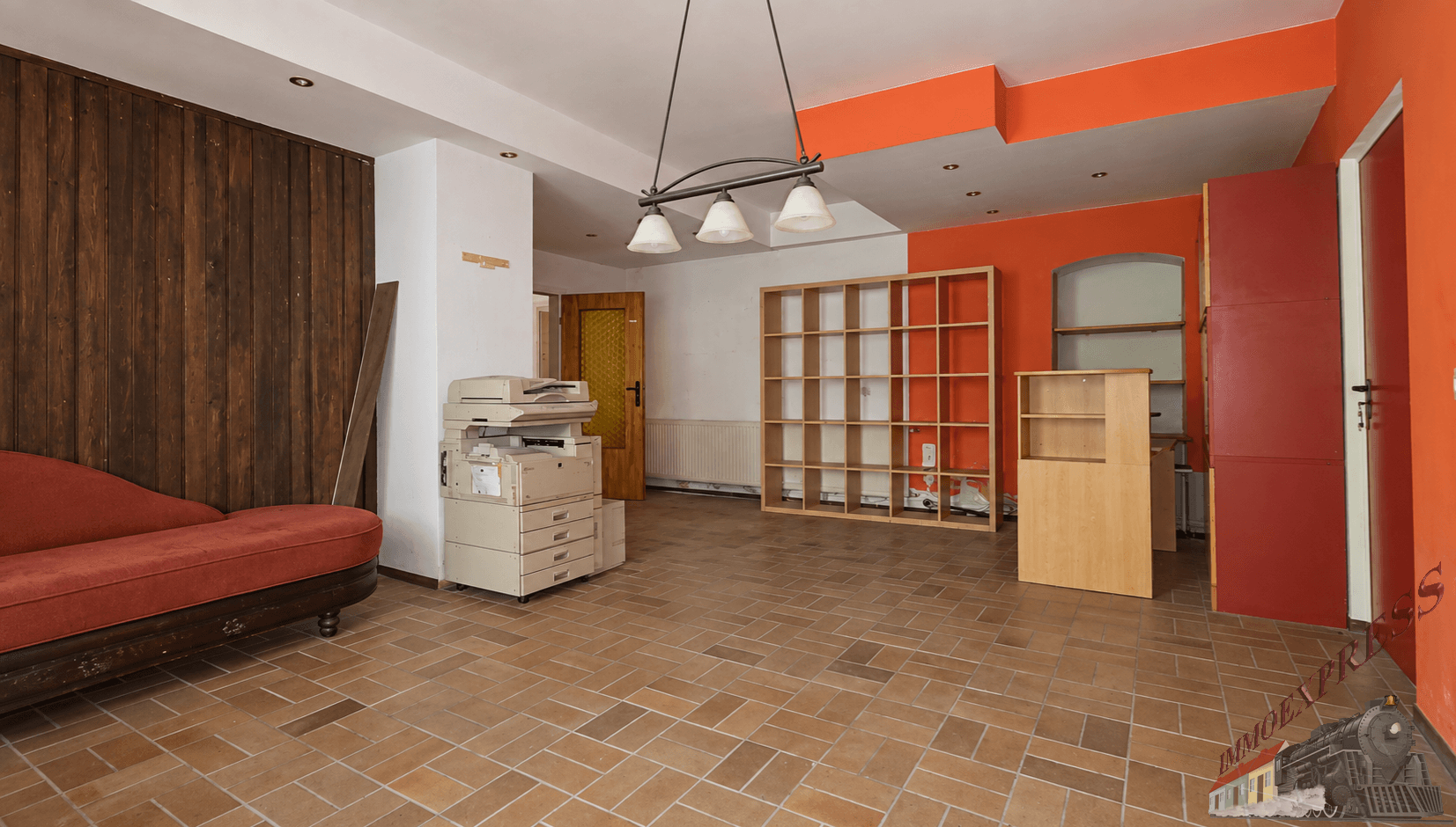 Geräumiger Wohnbereich mit orangefarbenen Wänden, Fliesenboden und Holzvertäfelung, mit Chaiselongue.