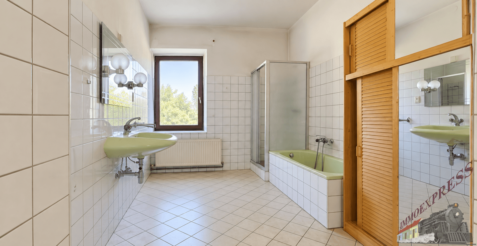 Badezimmer mit weißen Fliesen, grüner Badewanne und Waschbecken, sowie einer Duschkabine und Fenster.