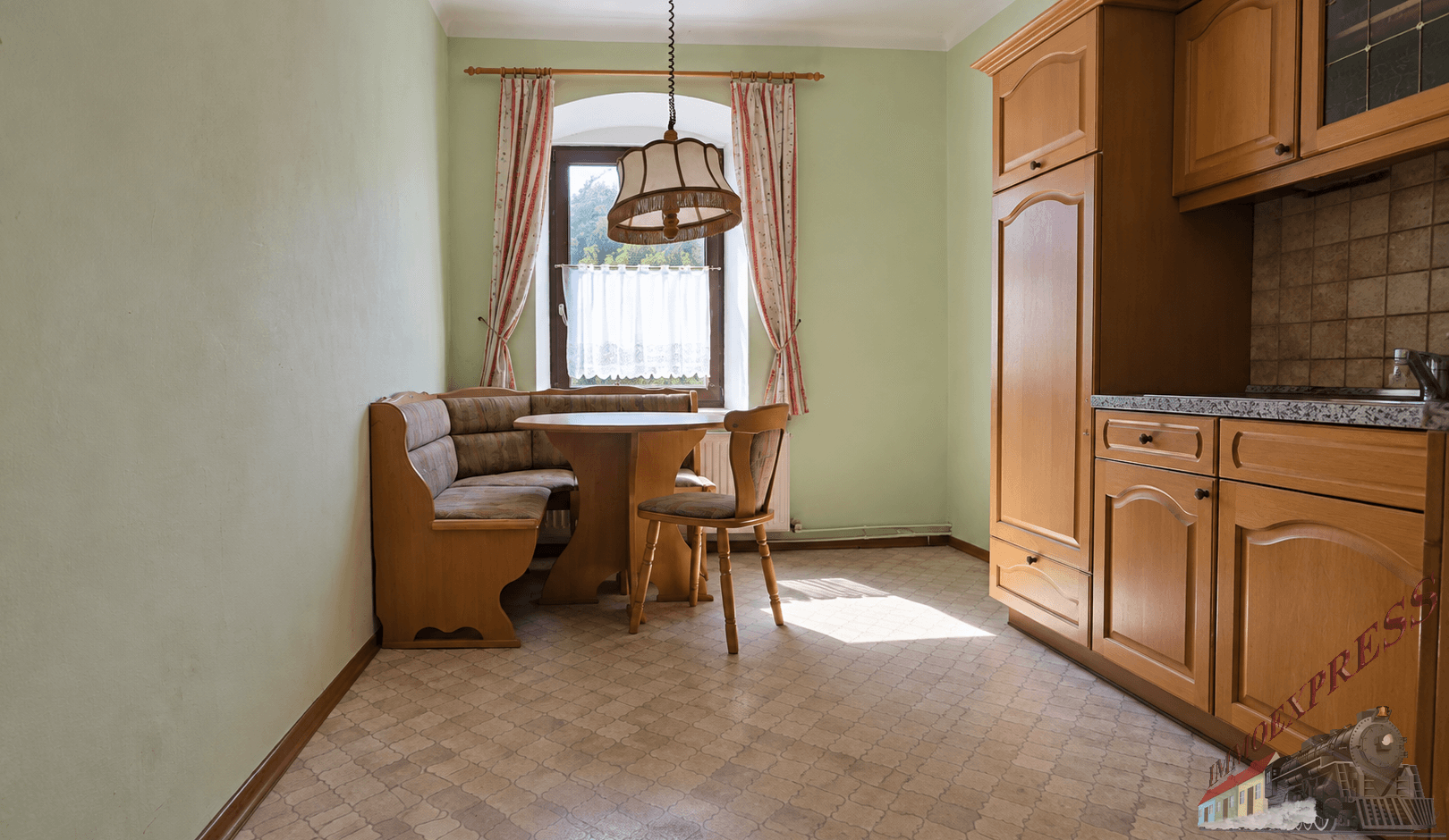 Küche mit hellgrünen Wänden, Linoleumboden, Holzschränken und einer gemütlichen Essecke.