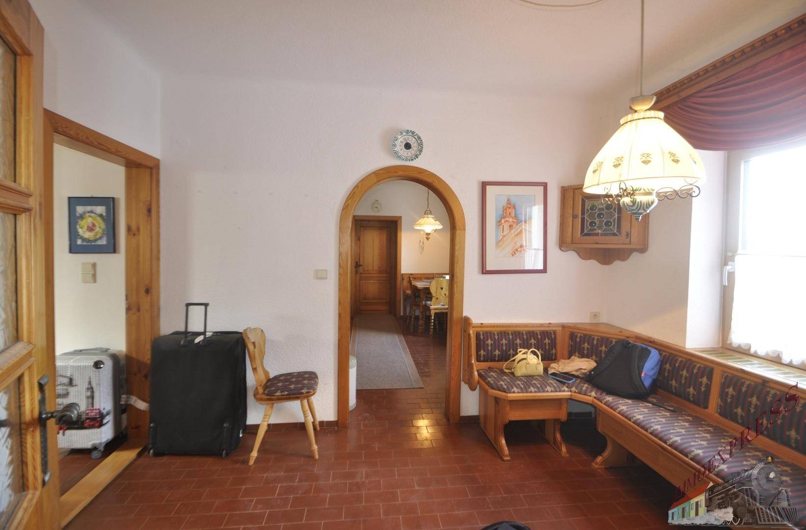 Wohnbereich im Landhausstil mit Eckbank, Terrakottafliesen und Durchgang zu weiteren Räumen.