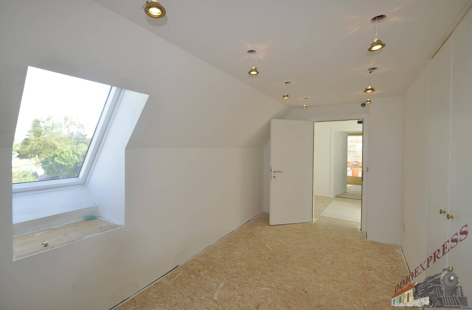 Helles Dachzimmer mit Dachfenster, OSB-Plattenboden und Einbaustrahlern, ideal für den Ausbau.