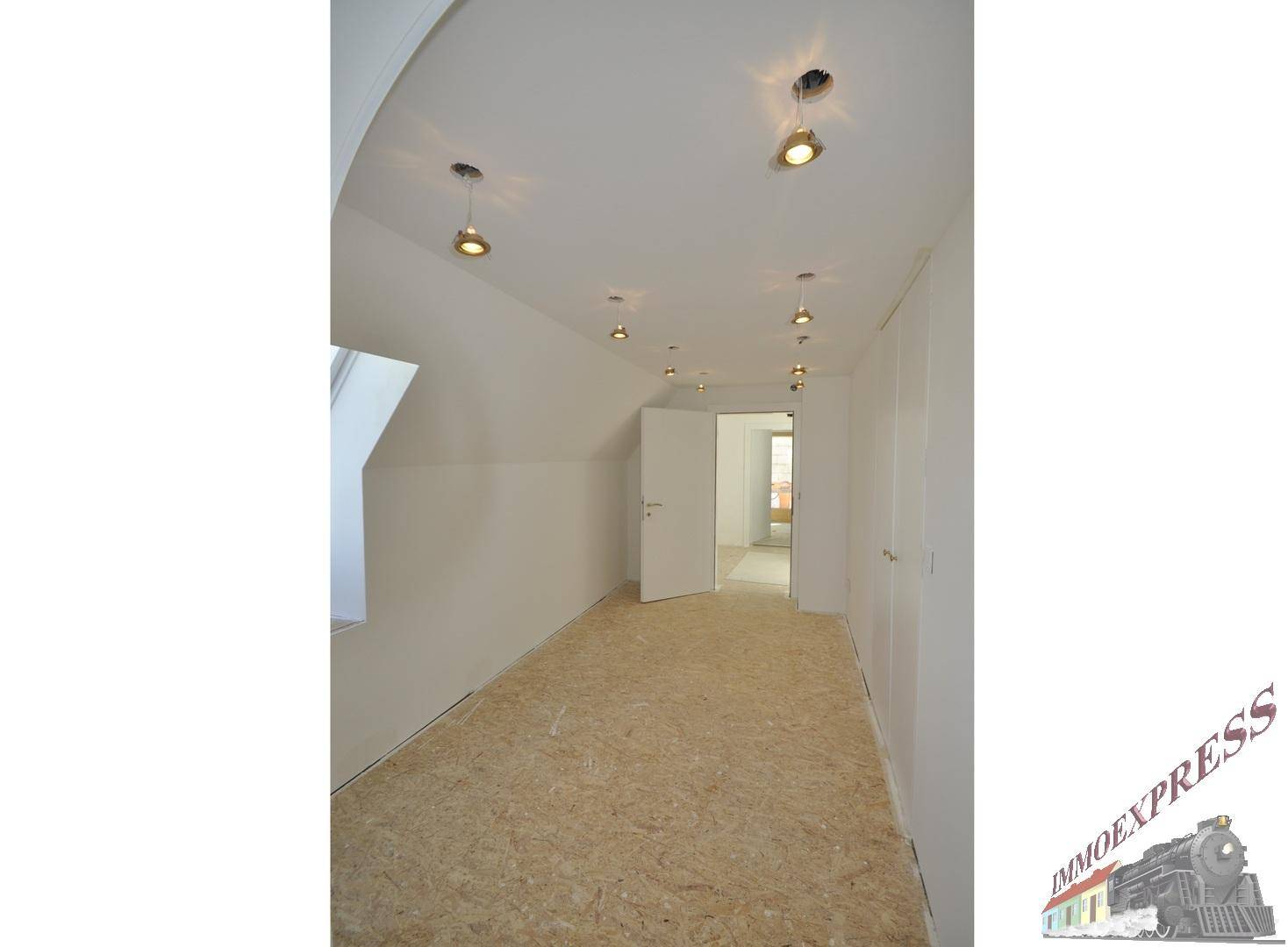 Unausgebauter Dachbodenraum mit OSB-Plattenboden und Einbaustrahlern, bereit für den Ausbau.
