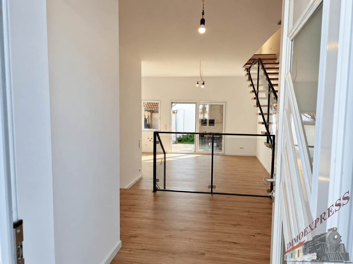 Heller, offener Wohnbereich mit modernem Treppenaufgang und Zugang zur Terrasse.
