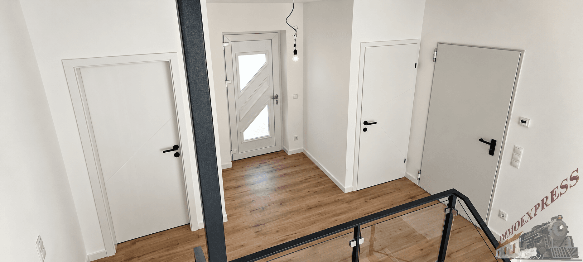 Heller Flur im Obergeschoss mit Blick auf den Eingangsbereich und moderne Innentüren.
