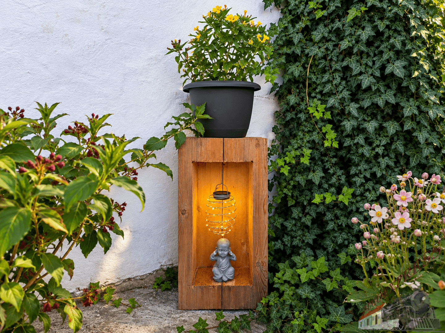 Detailaufnahme einer Gartenlaterne mit Buddha-Figur und üppiger Bepflanzung.