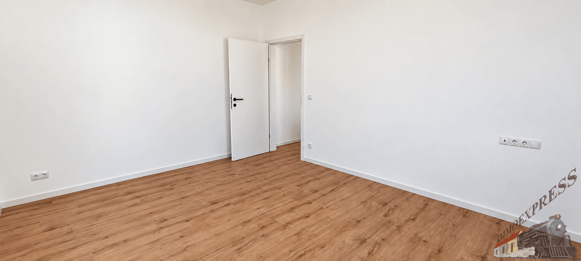 Leeres Zimmer mit Laminatboden und weißer Tür, bietet vielseitige Nutzungsmöglichkeiten.