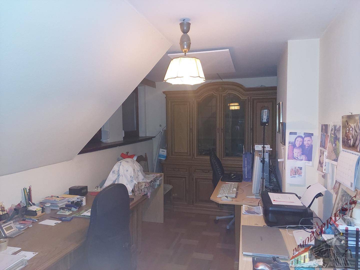 Dachgeschoss-Büro mit Schreibtischen, Holzschrank und Dachschräge.