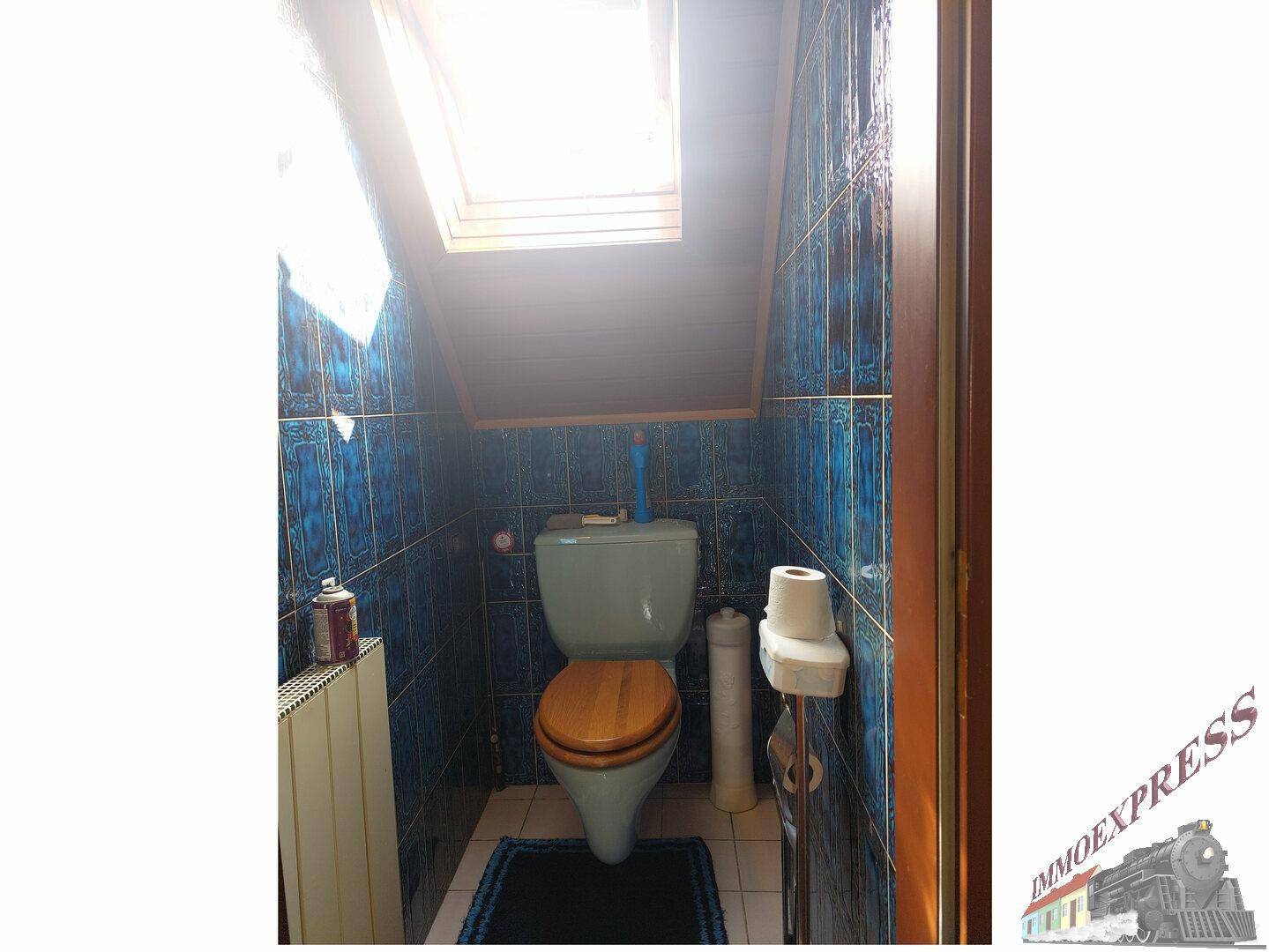 WC im Dachgeschoss mit blauen Fliesen, Toilette und Dachfenster.