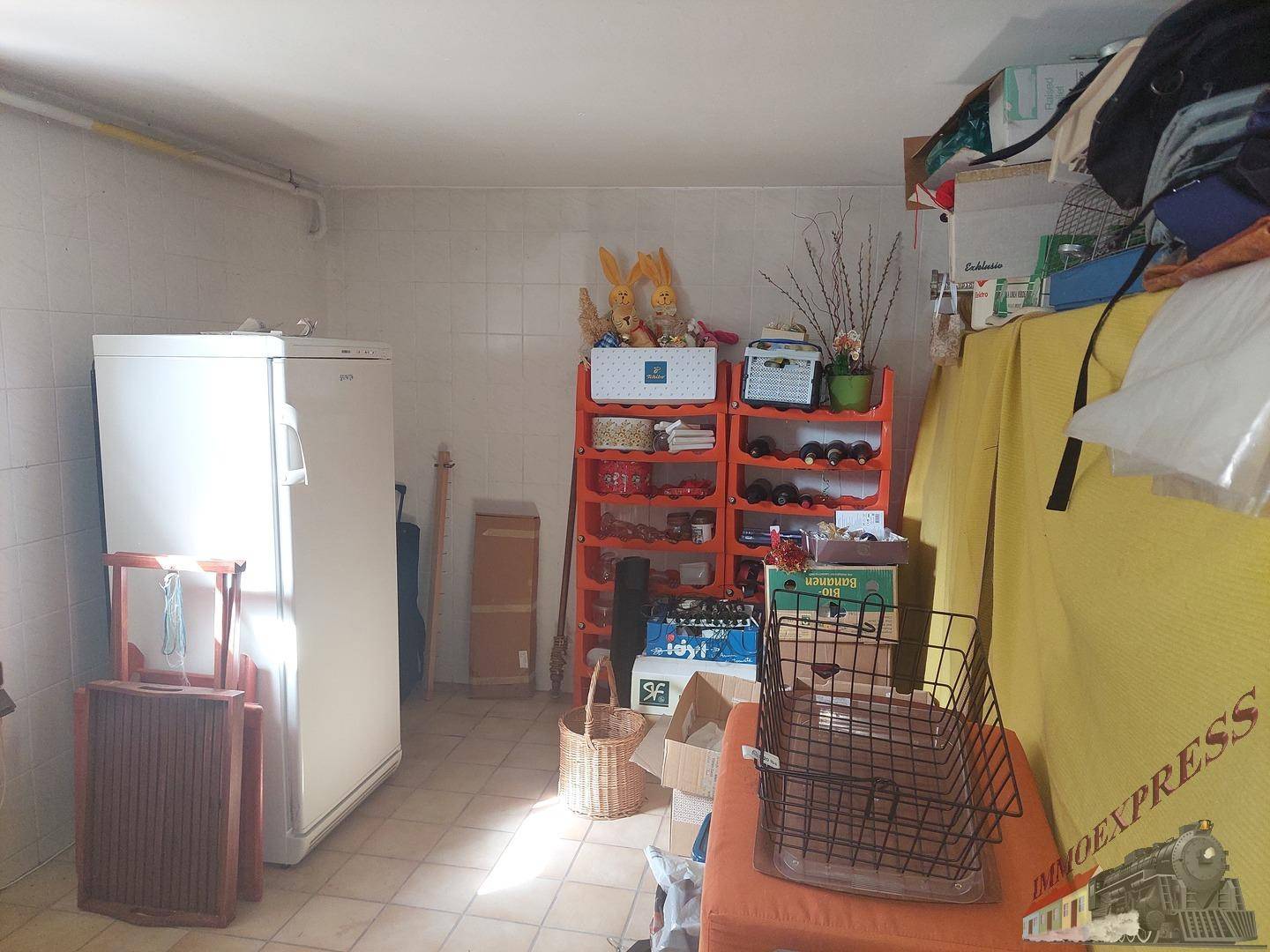 Abstellraum im Untergeschoss mit Regalen, Kühlschrank und Fliesenboden.