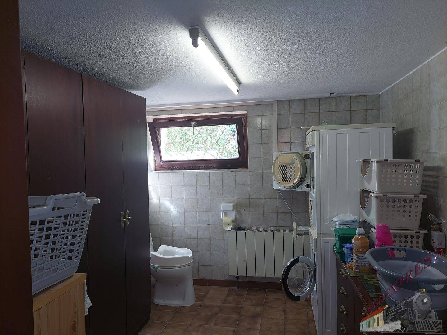 Waschküche im Untergeschoss mit Waschmaschine, Trockner und Fenster.