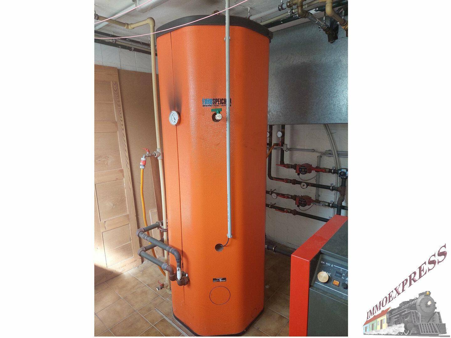 Detailansicht des großen orangefarbenen Warmwasserspeichers der Heizungsanlage.