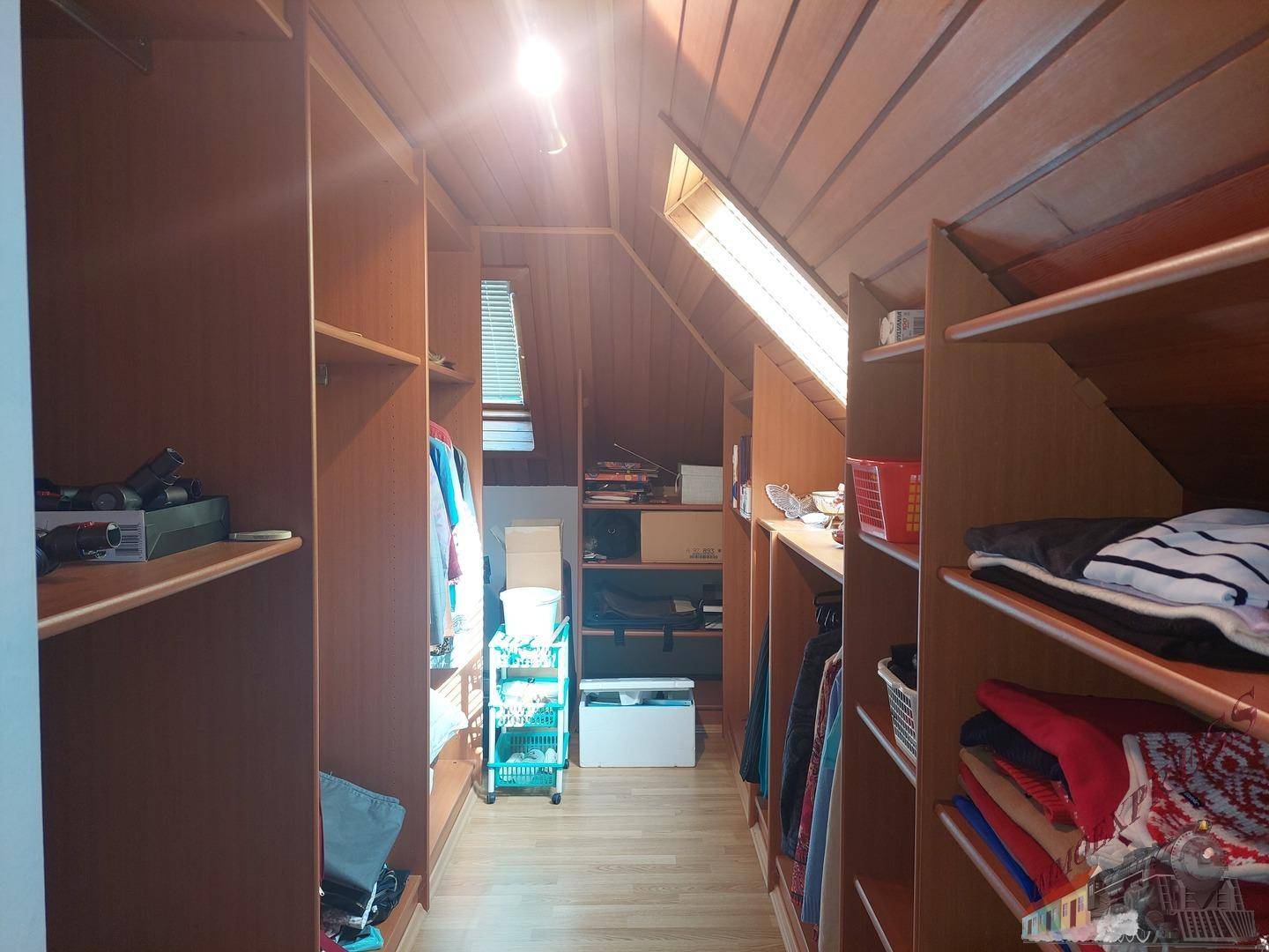 Begehbarer Kleiderschrank im Dachgeschoss mit Regalen und Dachfenstern.