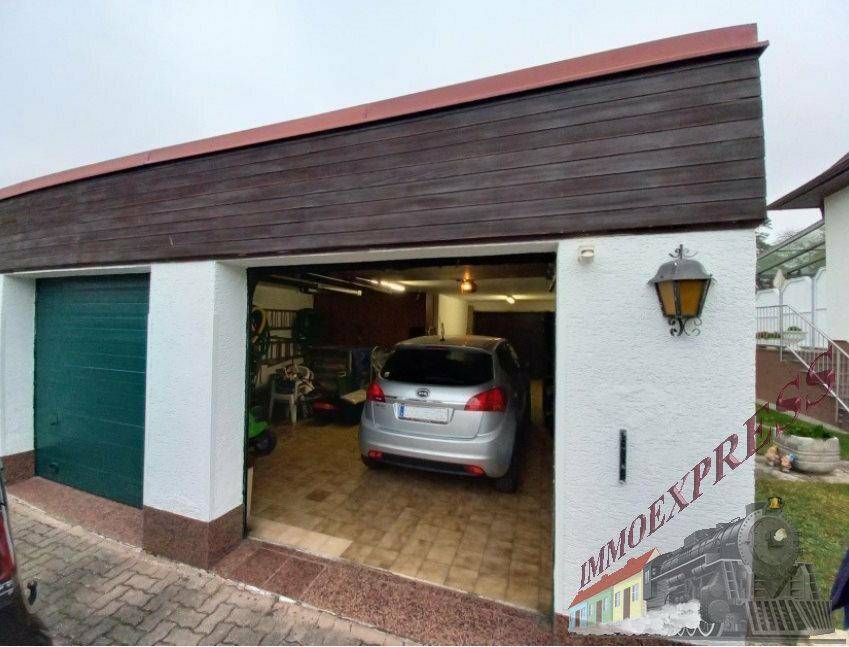 Doppelgarage mit einem geöffneten Tor, das ein geparktes Auto und Stauraum zeigt.