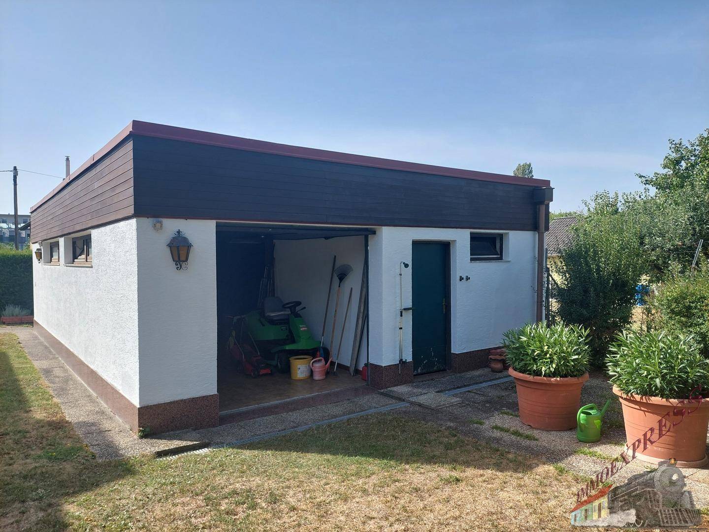 Außenansicht der Garage mit zwei Toren und einem separaten Seiteneingang zum Garten.