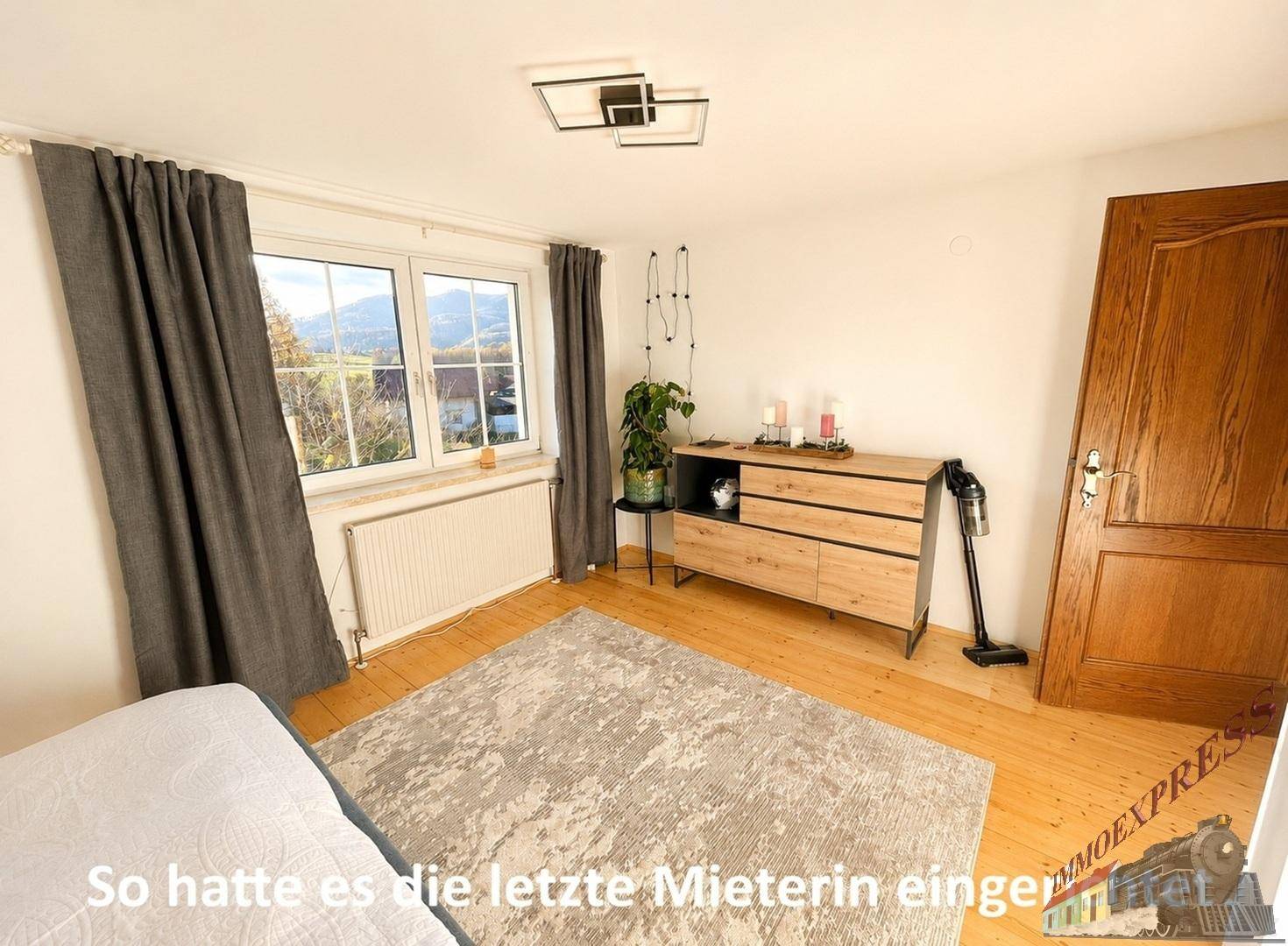 Schlafzimmer, eingerichtet von der Vormieterin, mit Kommode, Teppich und Vorhängen.