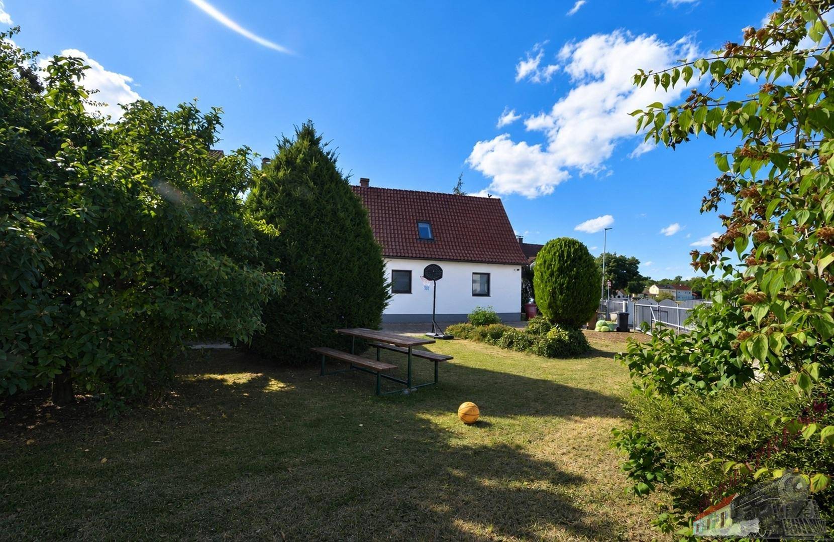 Großer Garten mit Rasen, Picknicktisch und Bäumen, ideal für Freizeitaktivitäten im Freien.