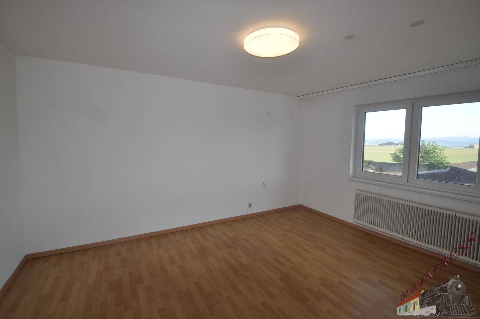 Helles Schlafzimmer mit Laminatboden, weißen Wänden und einem weiten Blick über die Landschaft.