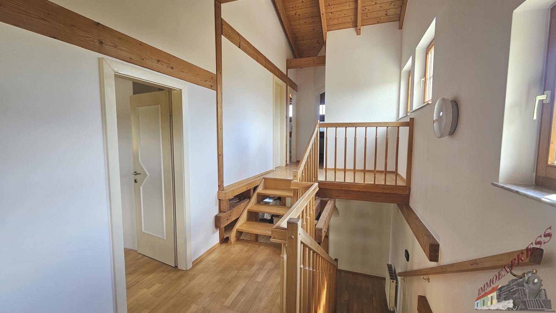 Heller Flur mit Holztreppe und Zugang zu weiteren Räumen im Obergeschoss.