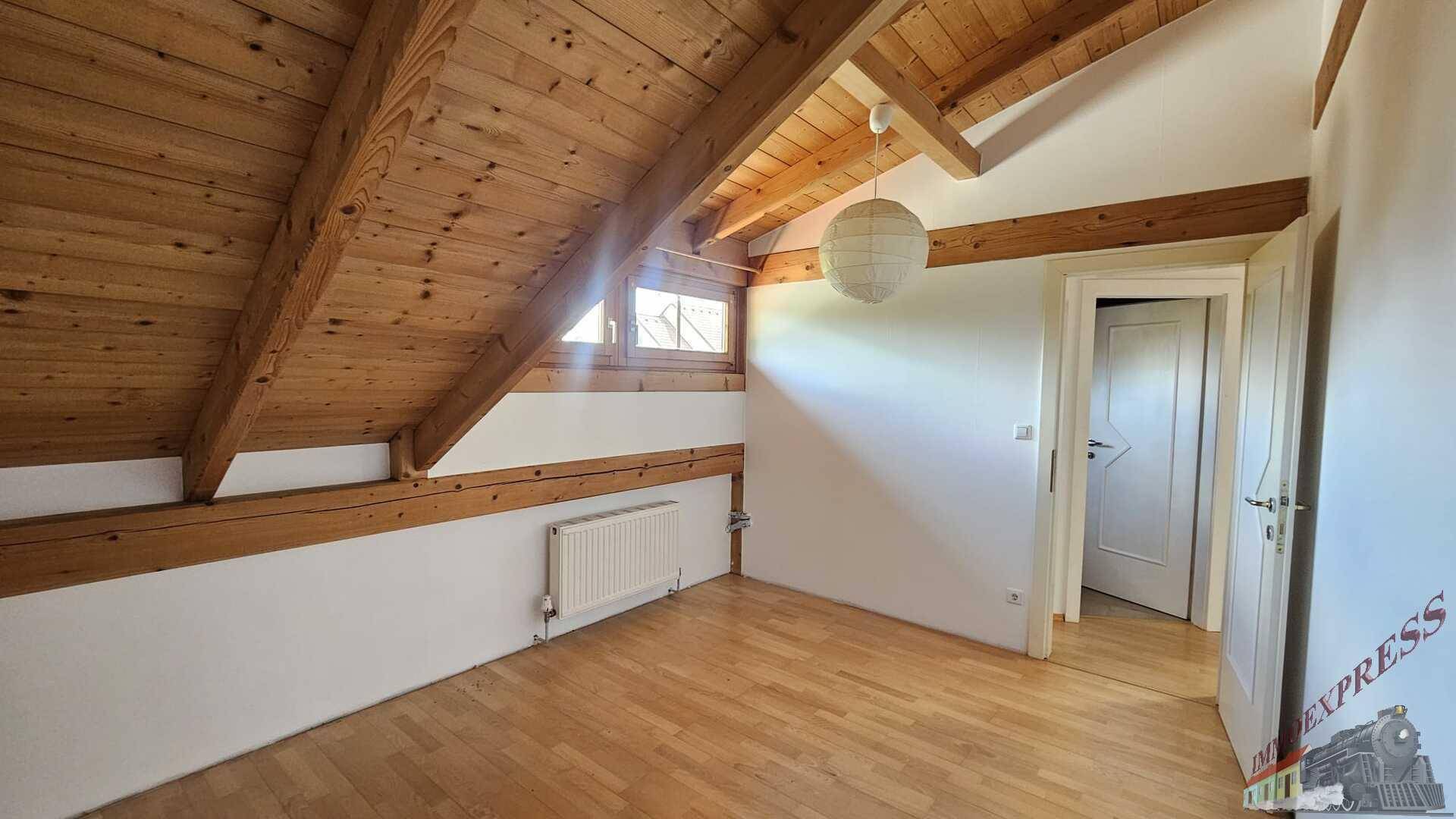Gemütliches Schlafzimmer im Dachgeschoss mit Holzbalken und schrägen Wänden.