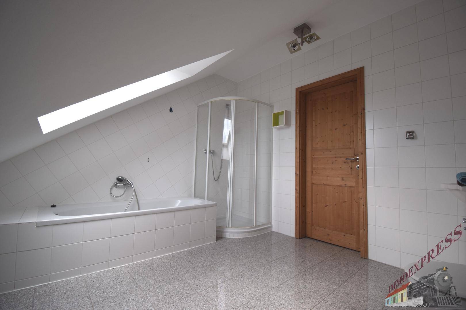 Modernes Badezimmer mit Badewanne, Eckdusche, weißen Fliesen und einem Dachfenster für natürliches Licht.