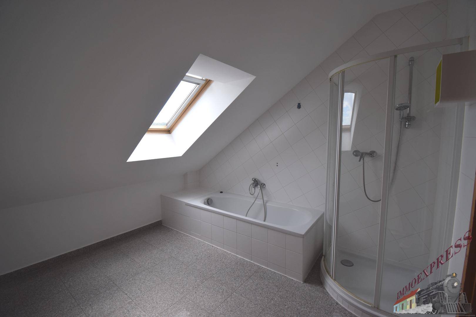 Geräumiges Badezimmer mit Badewanne, Duschkabine und viel Tageslicht durch das Dachfenster.