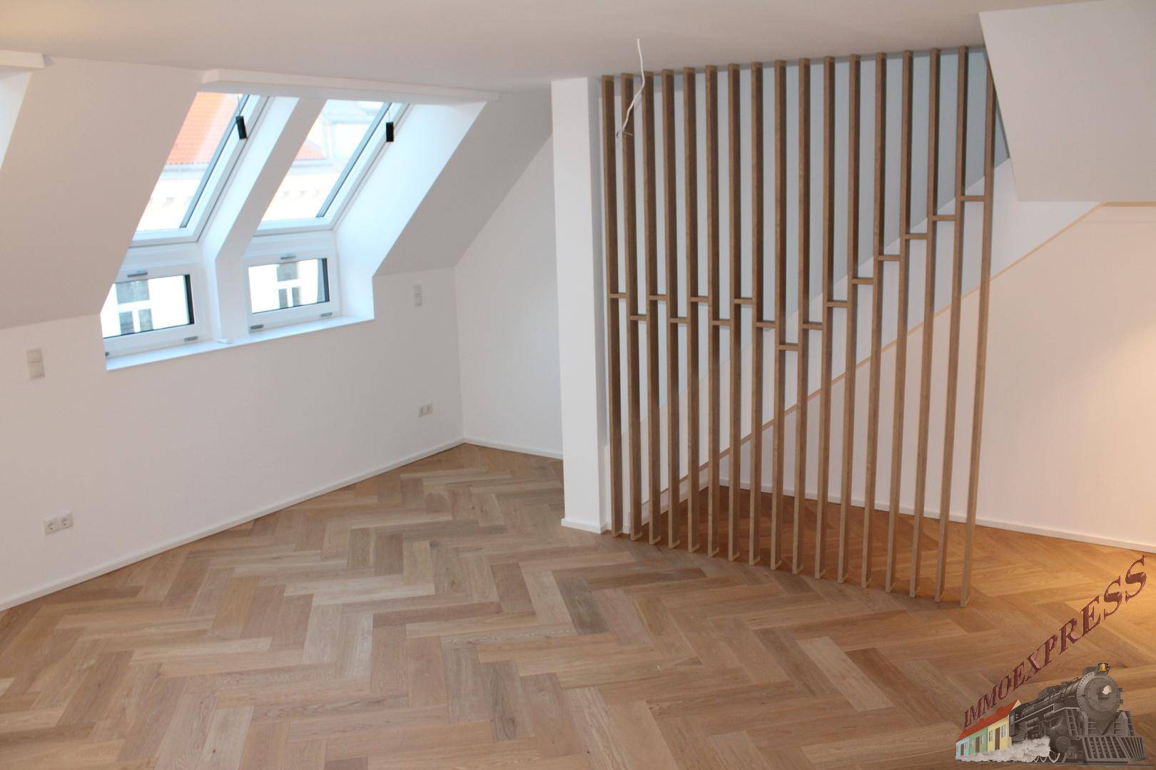 Heller Wohnbereich mit dekorativem Holz-Raumteiler, Dachfenstern und Fischgrätparkettboden.