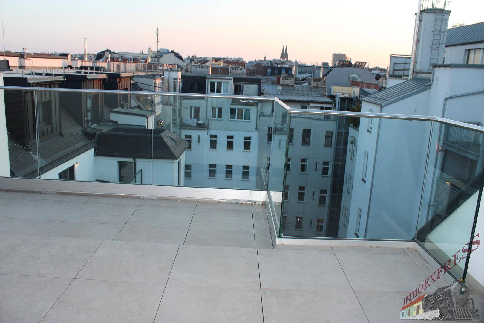 Große Dachterrasse mit Glasgeländer und weitem Blick über die Stadtlandschaft.