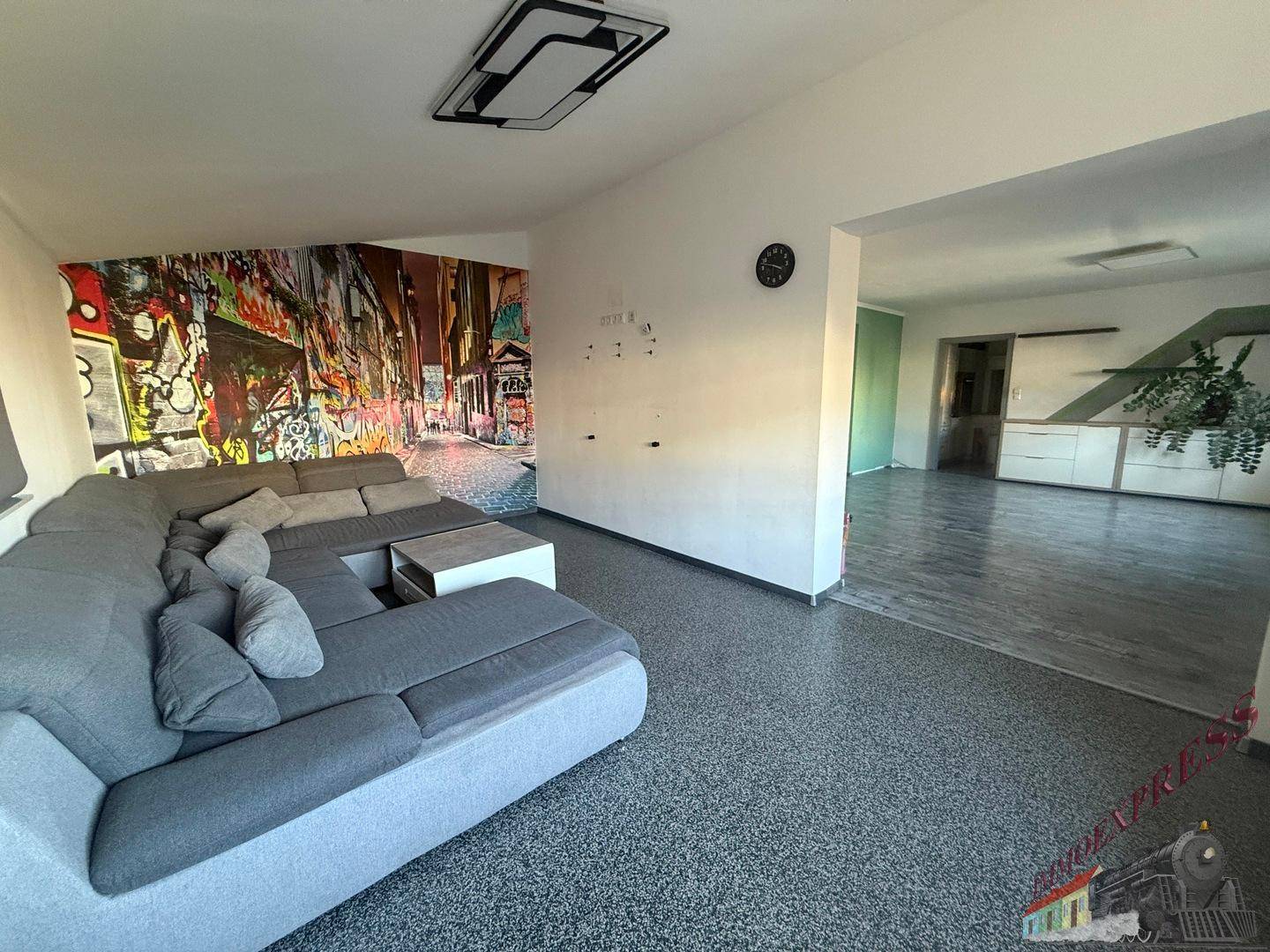 Geräumiges Wohnzimmer mit großem Ecksofa und moderner Wandgestaltung.
