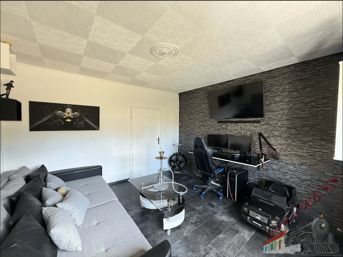 Modernes Wohnzimmer mit großem Fernseher, Gaming-Setup und dunkler Steinwand.