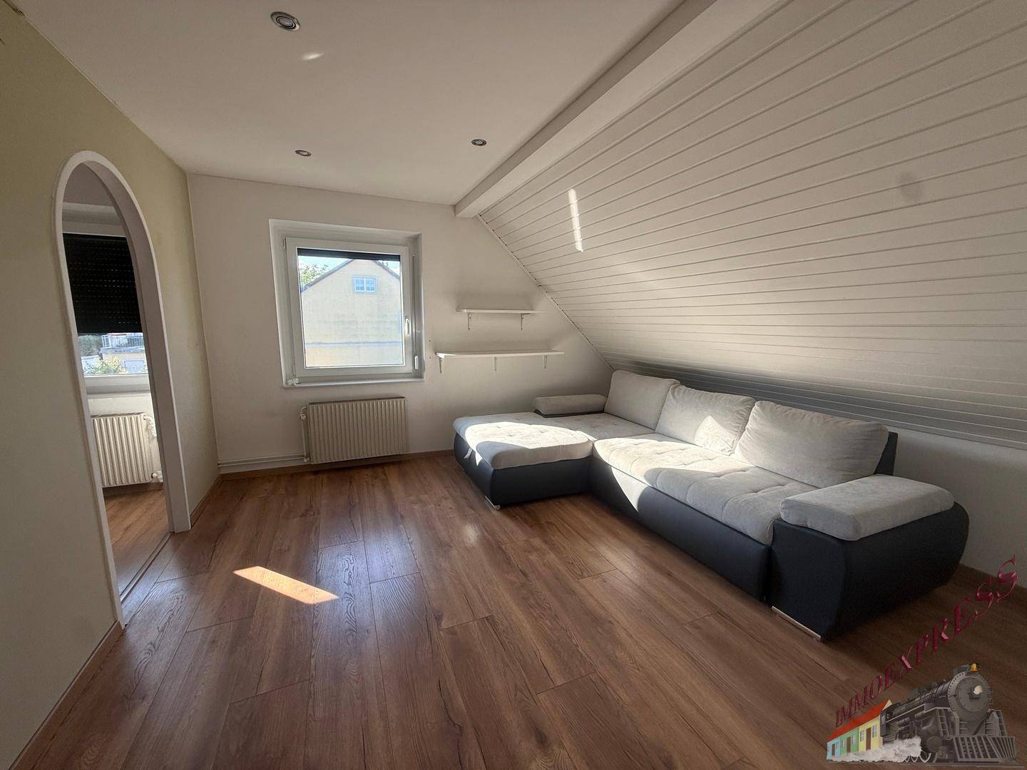 Helles Wohnzimmer im Dachgeschoss mit Holzboden und schrägen Wänden.