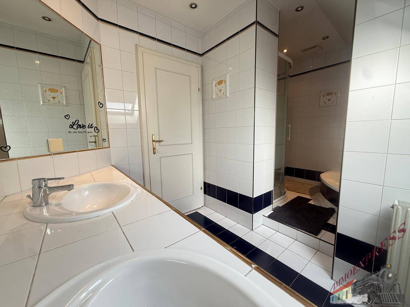 Badezimmer mit weißen Fliesen, Badewanne, Dusche und Einzelwaschbecken.