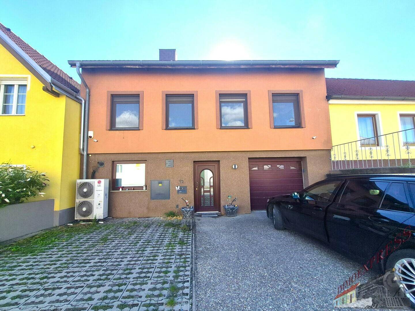 Vorderansicht des Hauses mit Einfahrt, Garage und Wärmepumpe.