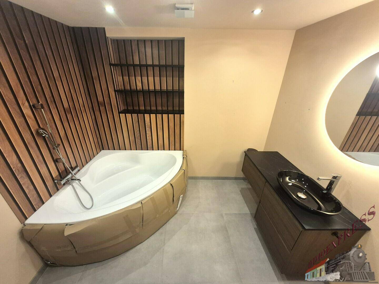Modernes Badezimmer mit Eckbadewanne, Holzverkleidung und beleuchtetem Spiegel.