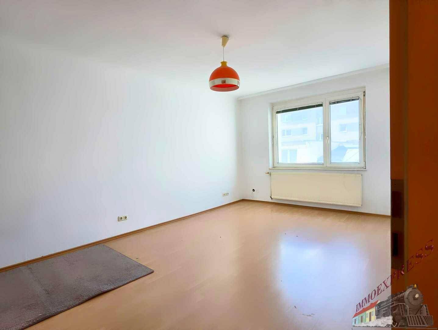 Geräumiges Schlafzimmer mit Laminatboden, großem Fenster und viel Tageslicht.