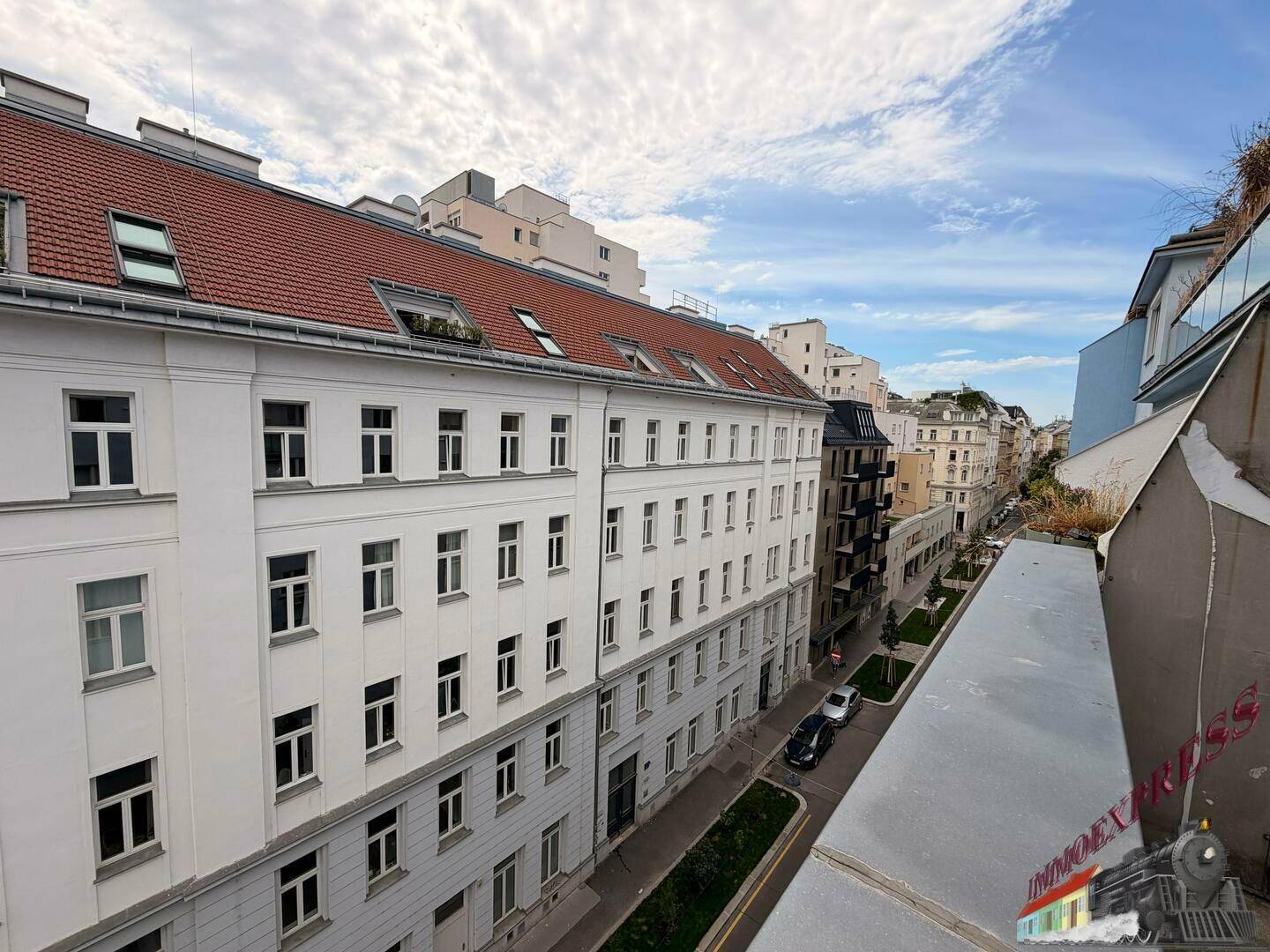 Weitblick über eine ruhige Stadtstraße mit klassischen Gebäuden und einem blauen Himmel mit Wolken.