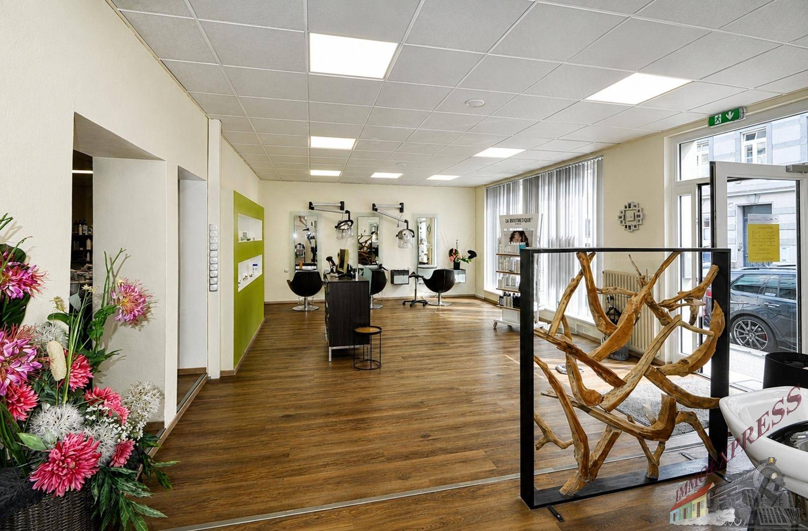 Heller Friseursalon mit Holzboden, großen Spiegeln und modernen Frisierstühlen, offen gestaltet.