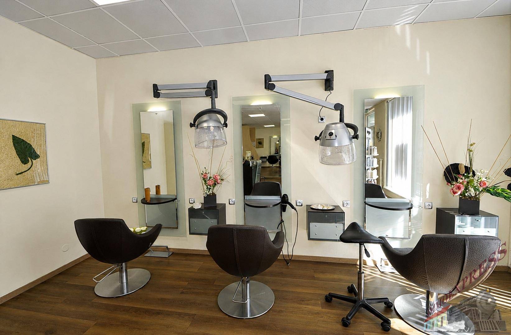 Frisierplätze mit Wandspiegeln, Trockenhauben und dunklen Ledersesseln in einem Salon, funktional und elegant.