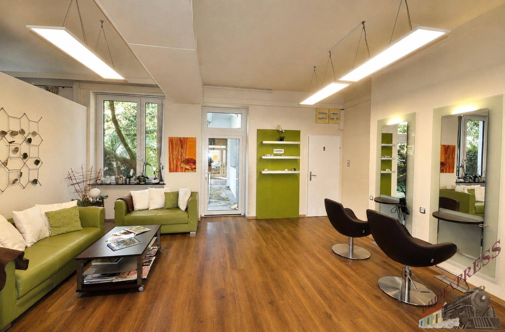 Wartebereich mit grünen Sofas, Couchtisch und Blick ins Grüne durch große Fenster, gemütlich und hell.