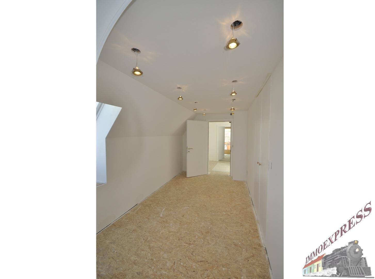 Heller Dachbodenraum im Rohbau mit Dachfenster und Einbauschränken, bereit zum Ausbau.