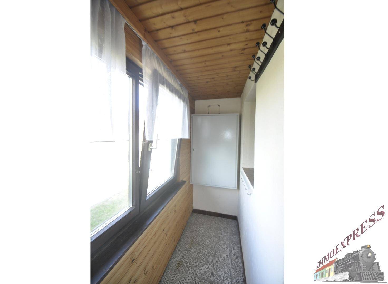 Schmale Loggia mit Holzverkleidung, Fenstern und Blick nach draußen, ideal zum Entspannen.