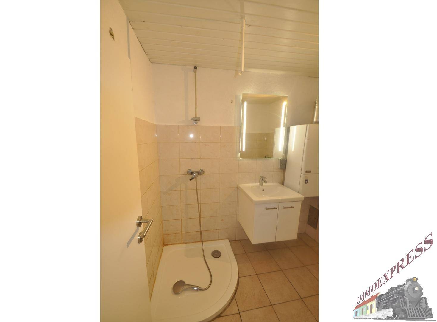 Helles Badezimmer mit Duschwanne, Waschbecken und Wandspiegel, ausgestattet mit beigen Fliesen.