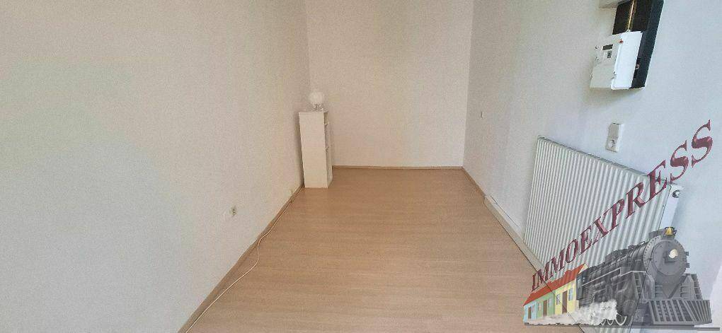 Schlichtes, leeres Zimmer mit hellem Laminatboden und weißen Wänden, ideal als Schlaf- oder Arbeitszimmer.