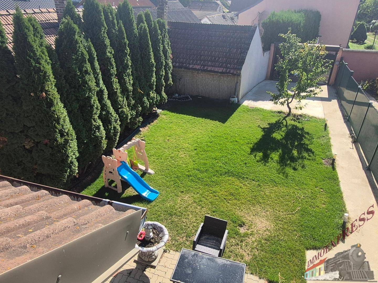 Blick von oben auf den gepflegten Garten mit Rasen, Kinderrutsche und Grillbereich.