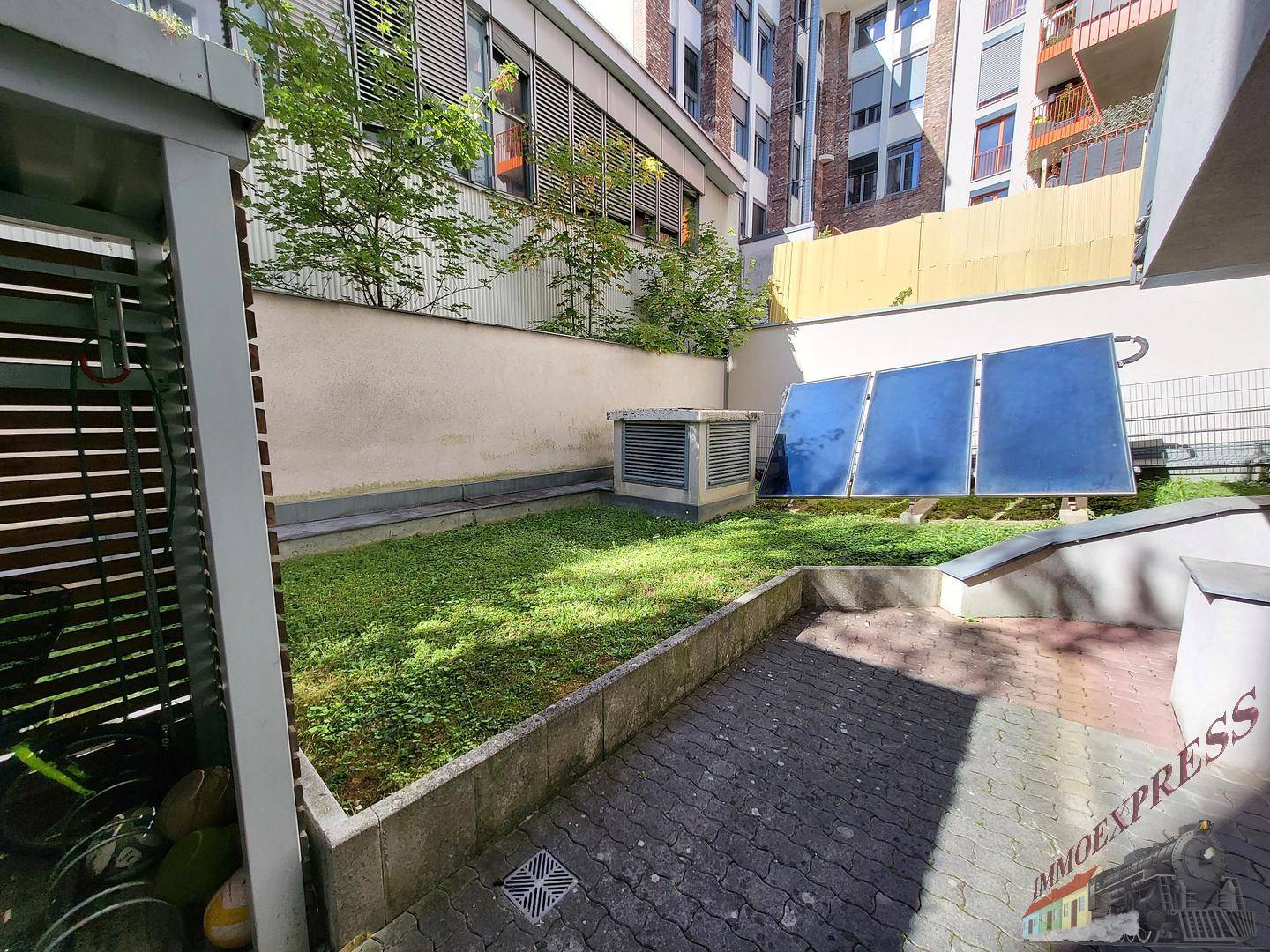 Kleiner Gartenbereich mit Rasenfläche und Solarpaneelen auf dem Dach.