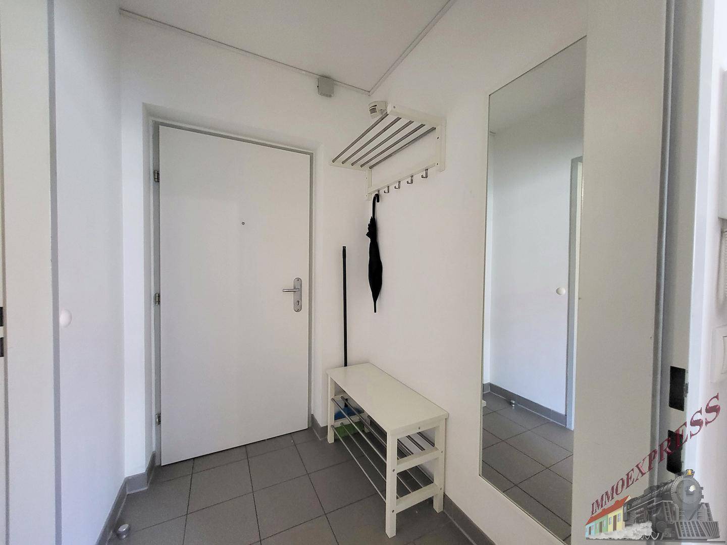 Eingangsbereich mit Garderobe, Spiegel und Fliesenboden.