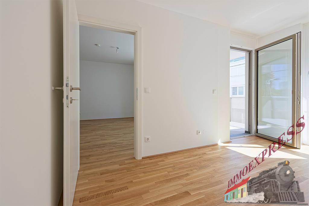 Lichtdurchfluteter Raum mit Parkettboden und Zugang zu einem Balkon sowie weiteren Zimmern.